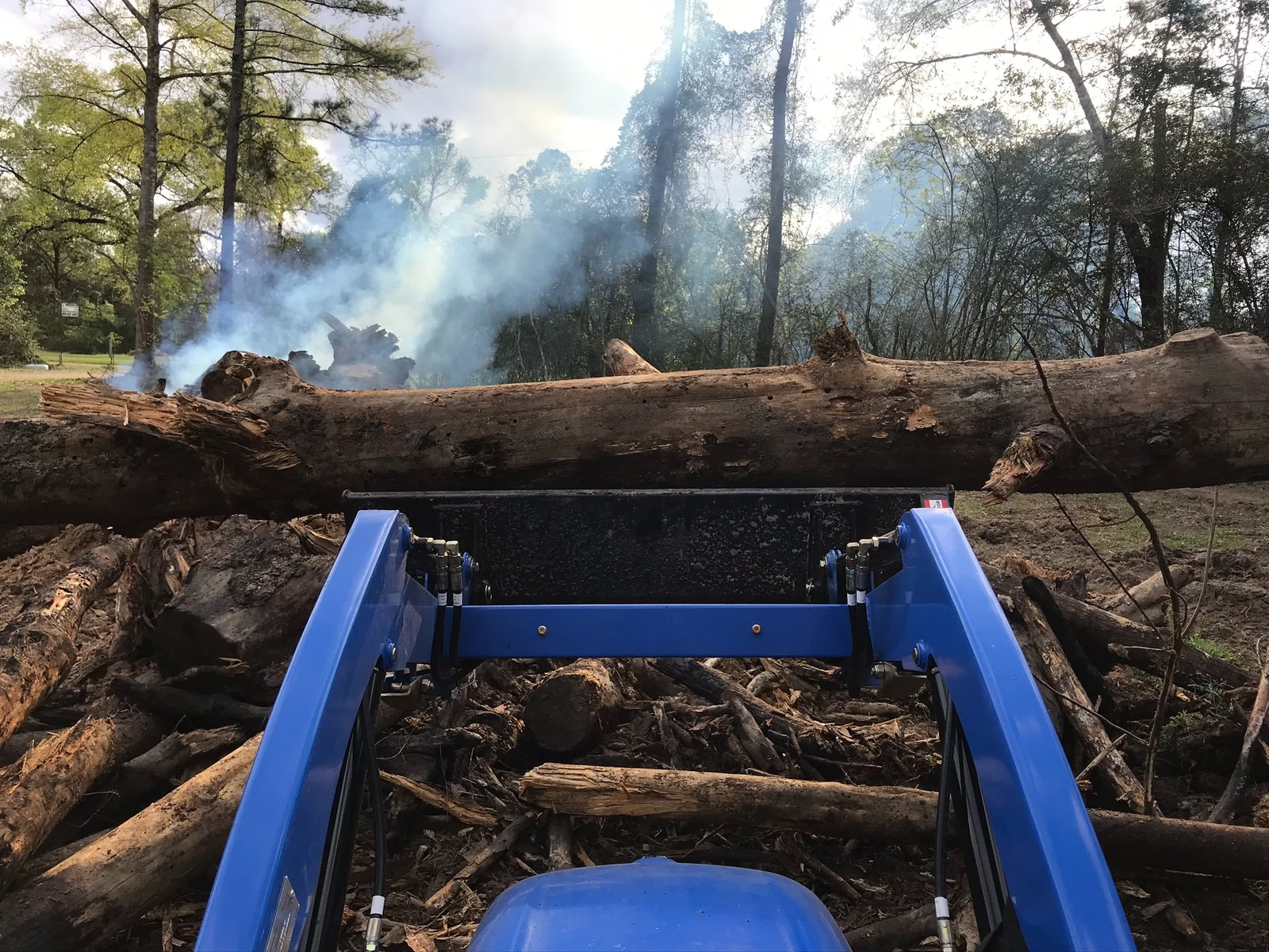 Front loader moving large logs and debris